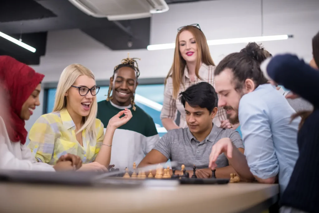 Jogos em inglês em grupo: amigos riem em volta de um tabuleiro durante a partida