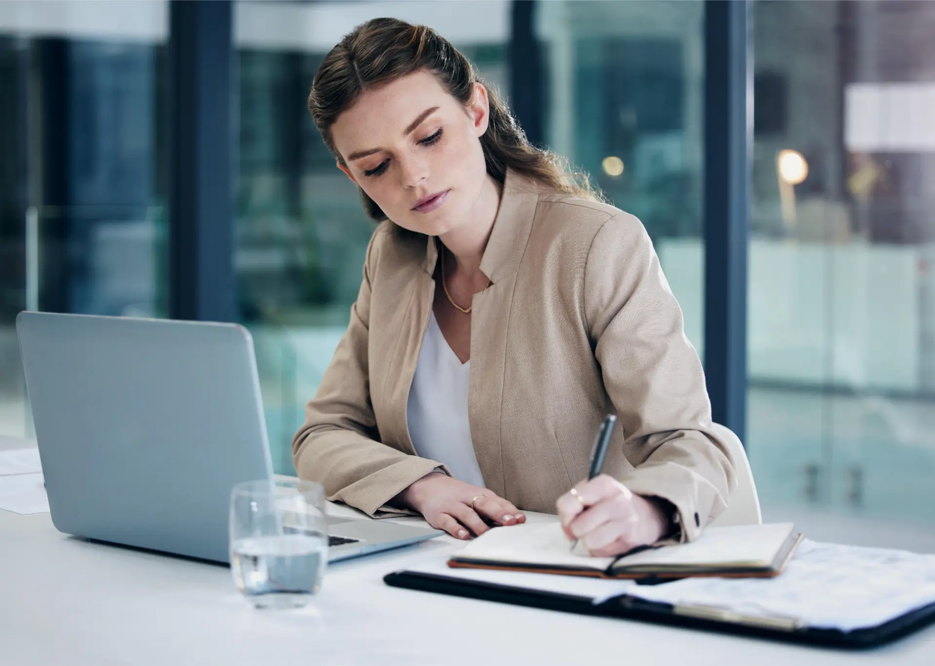 Vocabulário em inglês no trabalho: mulher anota palavras mais precisas ao lado do laptop