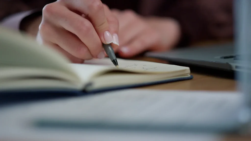 Alternativas ao very em inglês anotadas à mão em um caderno aberto ao lado do laptop