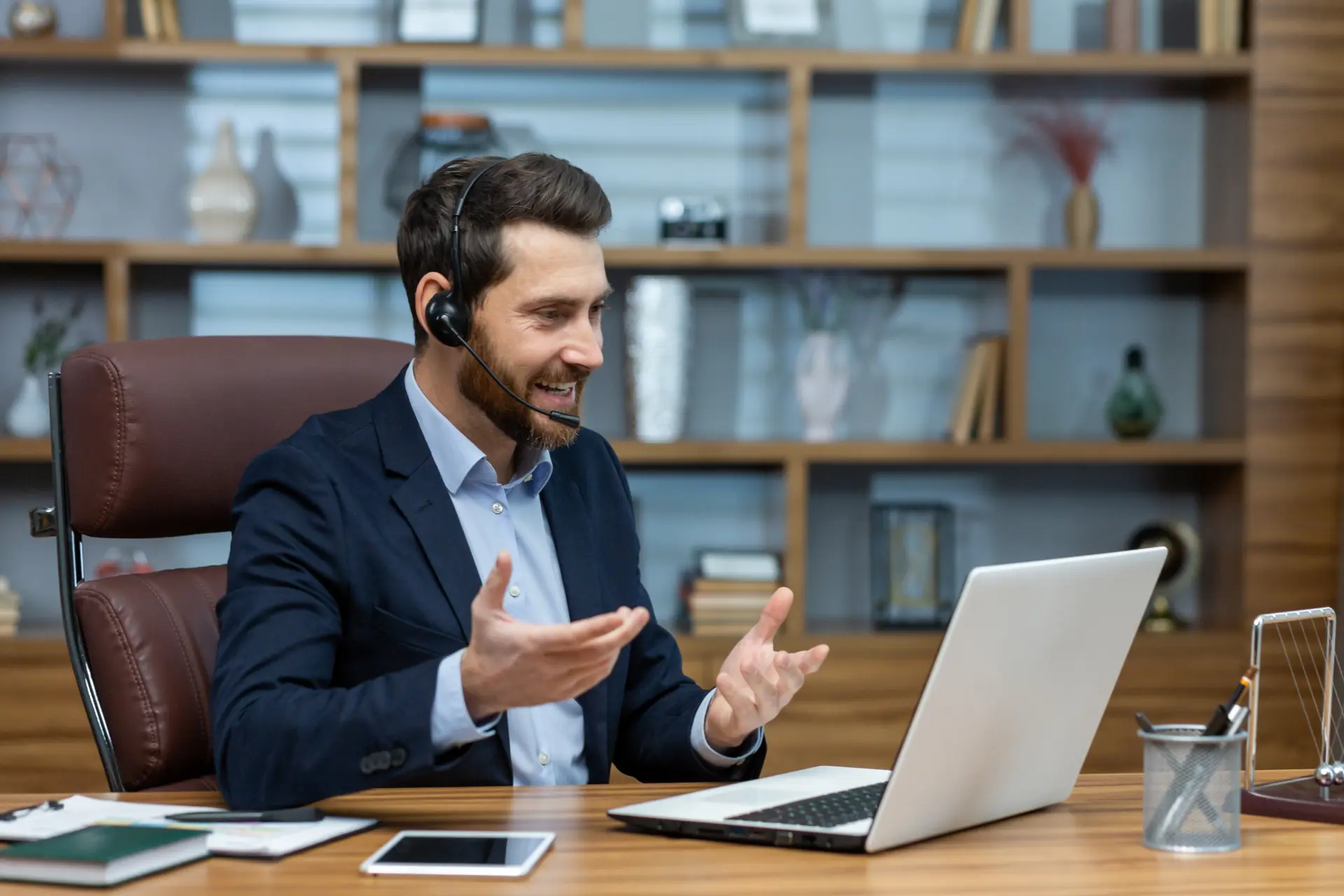 Inglês para reuniões: homem de headset fala e gesticula durante uma reunião de trabalho no laptop