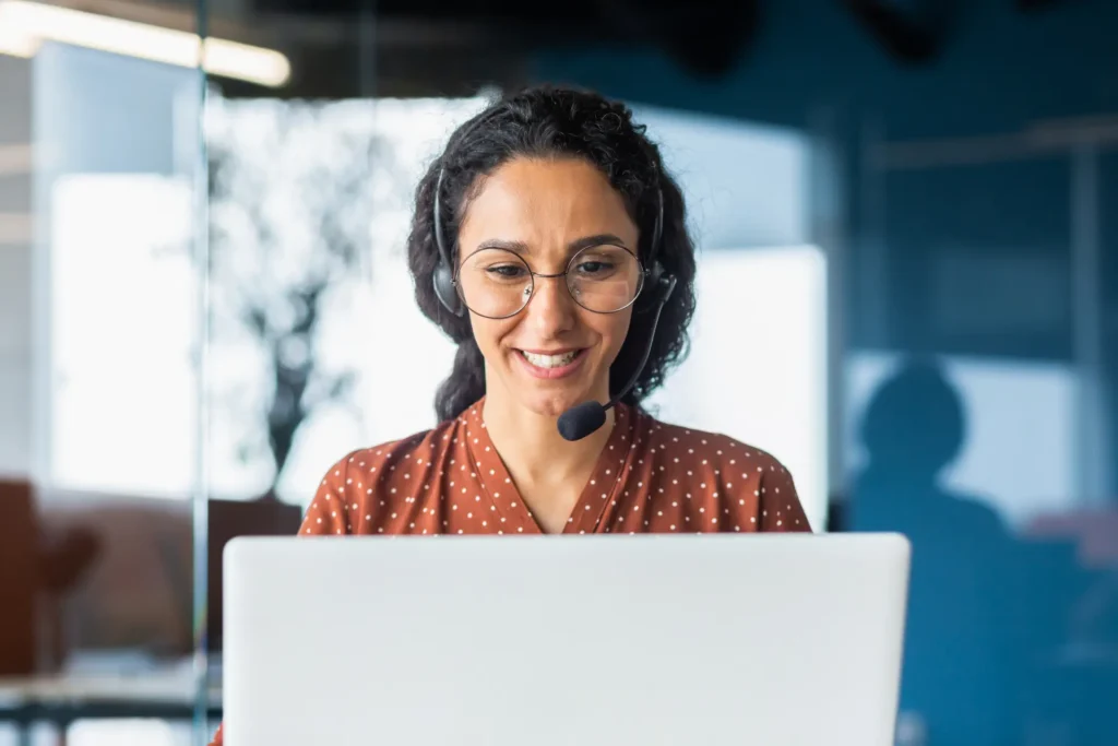 Frases em inglês para reuniões: mulher de headset abre a call sorrindo diante do laptop
