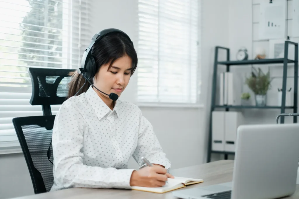 Profissional com headset anotando expressões em inglês em escritório moderno