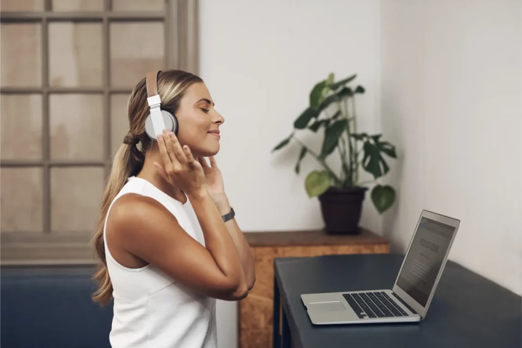 Profissional ouvindo música em inglês com fones no escritório